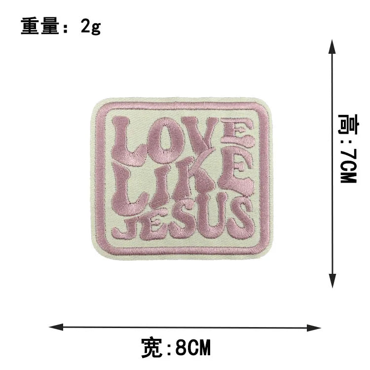 A square embroidered patch with the text LOVE LIKE JESUS in pink thread on a cream fabric.
