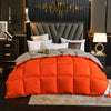 An orange goose down comforter duvet is displayed on a bed with dark decor and a gold chandelier.