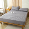 A gray waterproof mattress protector fitted sheet placed on a wooden bed frame.