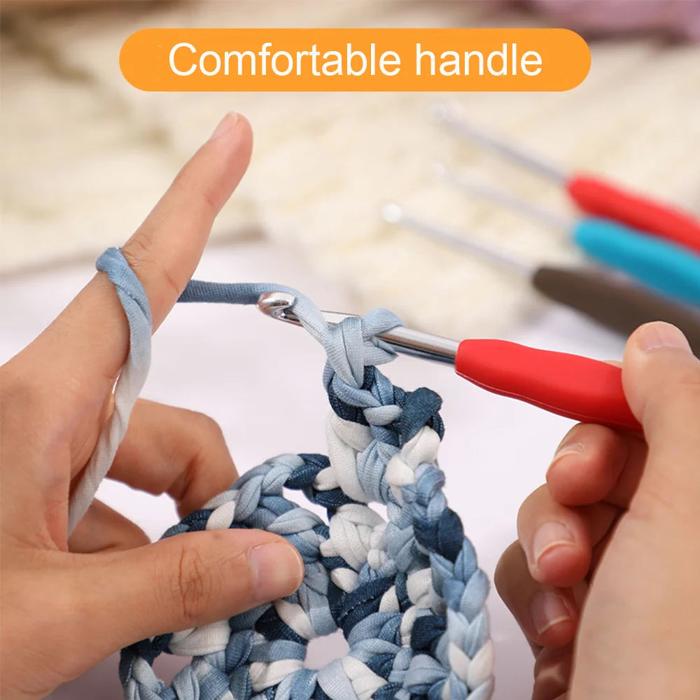 Hands are using a red precision aluminum crochet hook to work on a blue and white yarn craft.