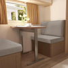 A beige upholstered seat cover is shown on a vehicle seat, with a wooden table and window in the background.
