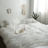 A pure white princess ruffle cotton bedding set displayed on a bed with white pillows and natural decor.