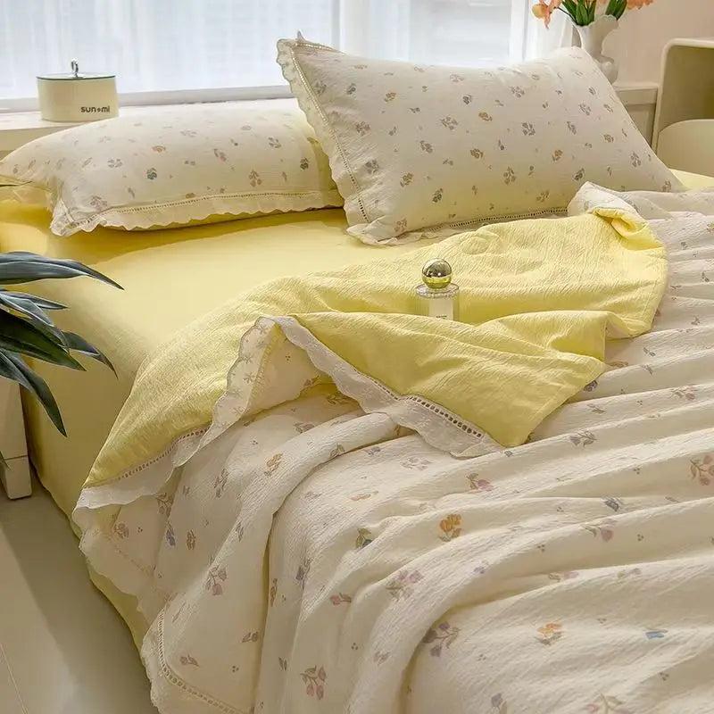 A yellow and white quilt blanket with a floral print is displayed on a bed, featuring matching pillows and fabric.