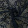 Dark blue floral lace sheer fabric gathered into a swirl, used as a curtain panel.