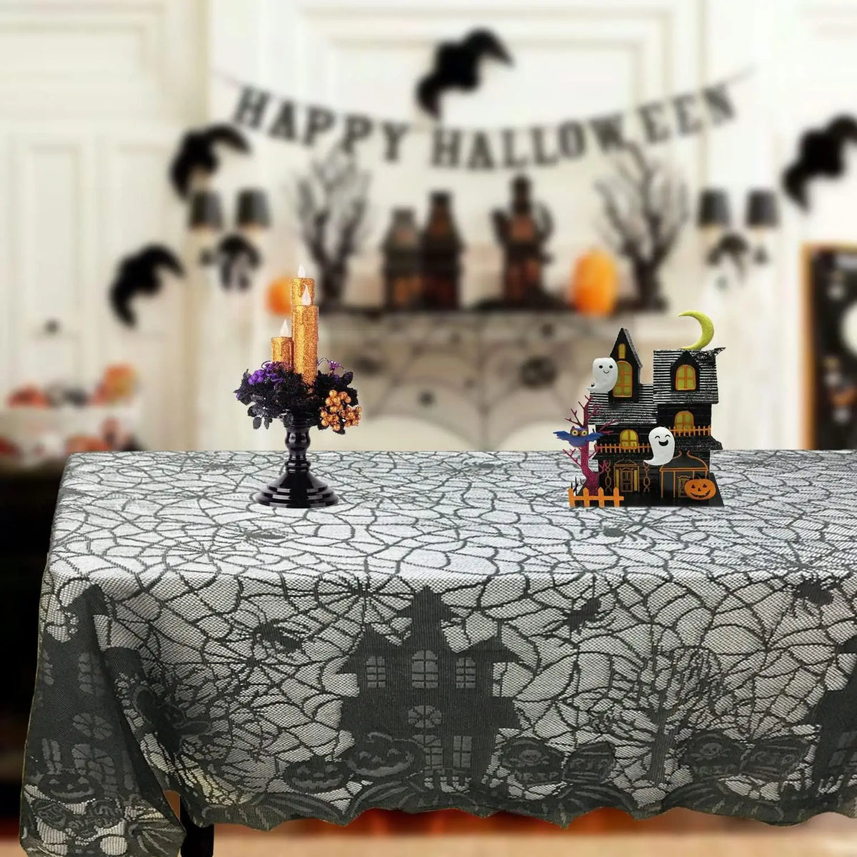 Black spider web lace table runner for Halloween featuring a miniature haunted house and candles.