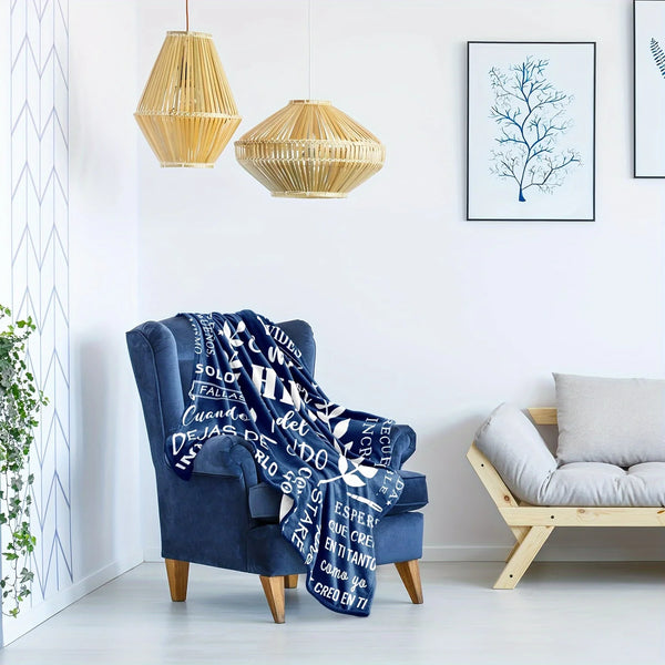A deep blue fleece blanket with white text hangs on a wooden chair in a bright room.