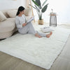 A woman relaxing on a white shag rug in a living room with indoor plants and a small side table.
