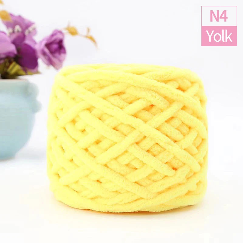 A ball of bright yellow chunky velvet knitting yarn with an open, textured weave.