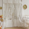 White vintage lace curtains with sheer fabric hang over a white door frame in a bright room.