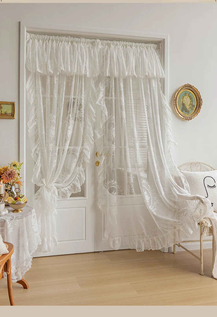 White vintage lace curtains with sheer fabric hang over a white door frame in a bright room.