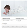 A baby is lying down wearing a white patterned cotton sleep sack for sleep.