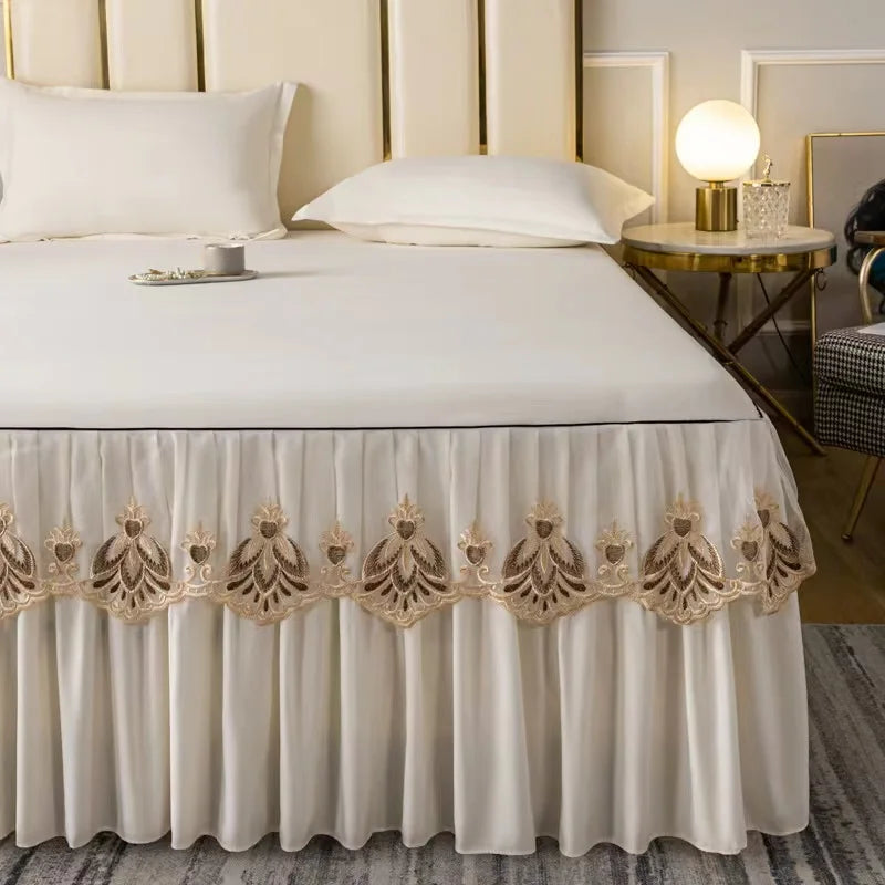 White embroidered cotton bedspreads and pillowcases with gold trim on a bed.