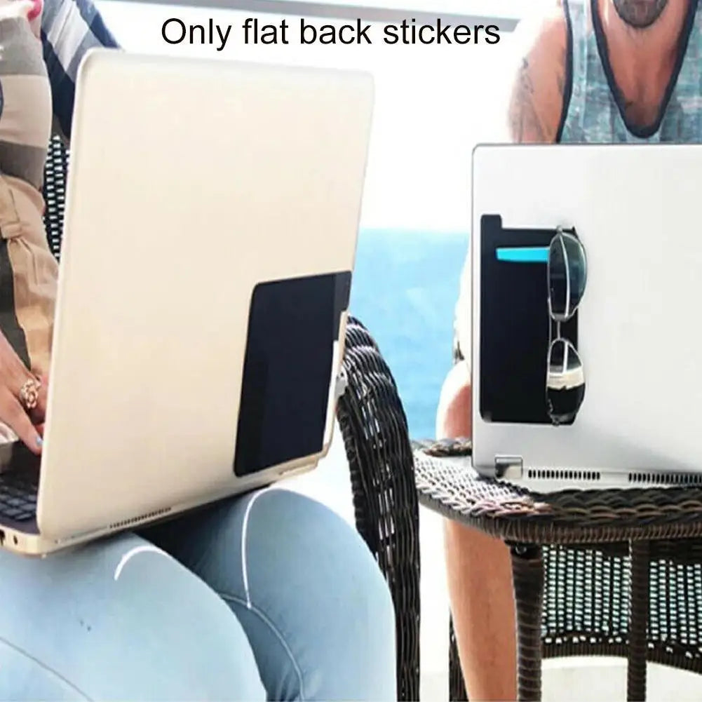 A laptop is shown open on a table next to a person, with flat back stickers visible.