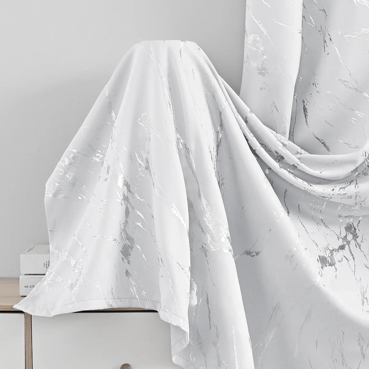 White marble printed curtain fabric draped elegantly against a light gray background.