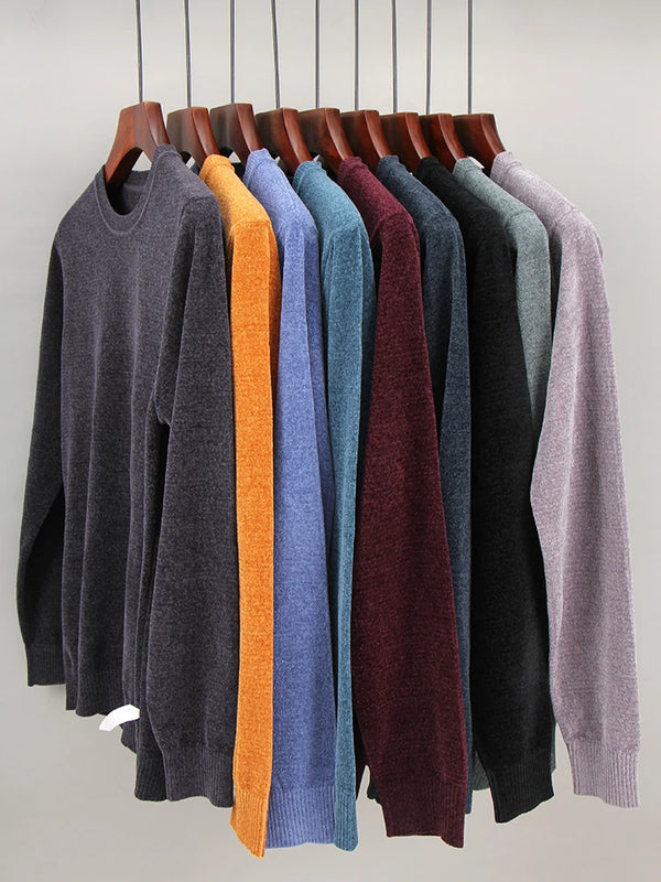 A display of various colored, chunky knit sweaters hanging on a rack.