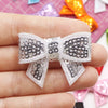A hand holds a white and black sequin bow patch for DIY decoration.