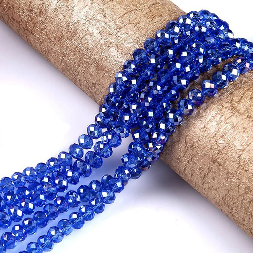 Blue faceted rondelle glass beads threaded onto a brown paper roll.