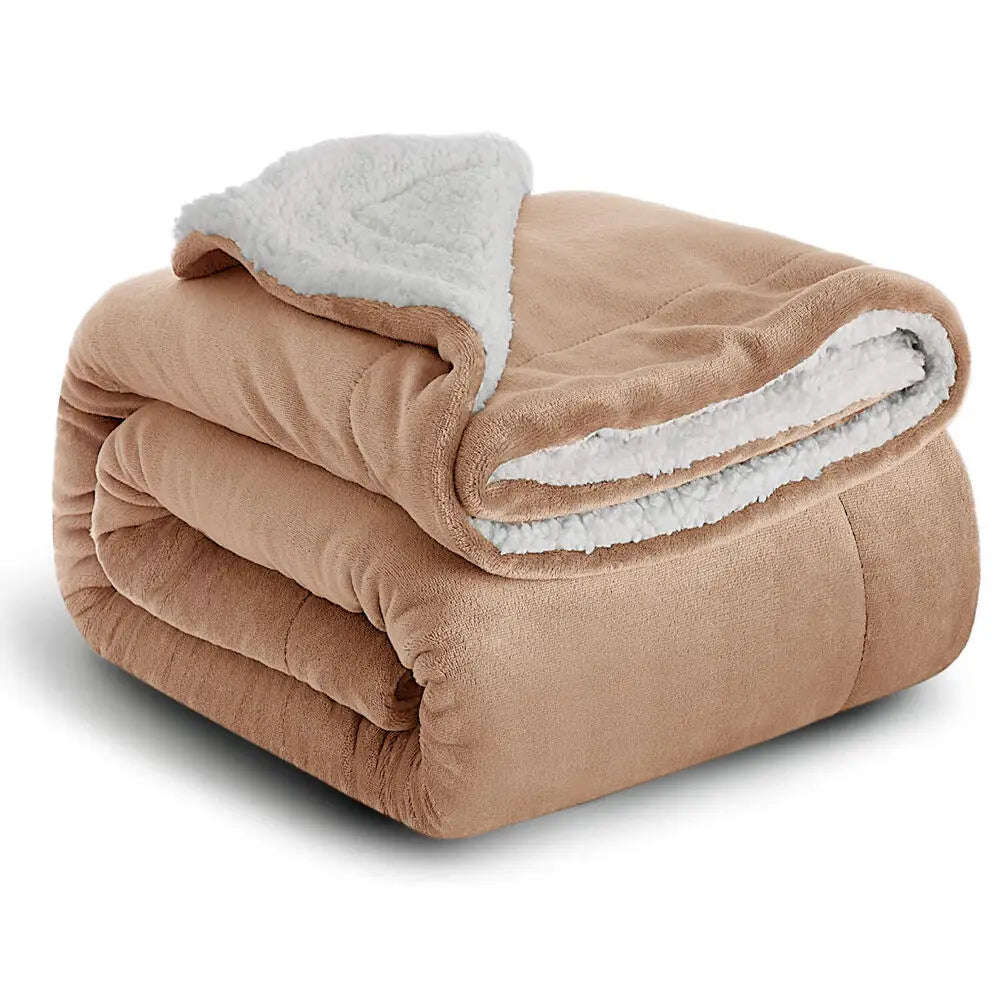 A tan sherpa fleece blanket rolled up, showing a fluffy white trim.