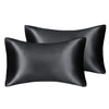A set of three black silky satin pillow covers, including two standard pillows and one larger sham.