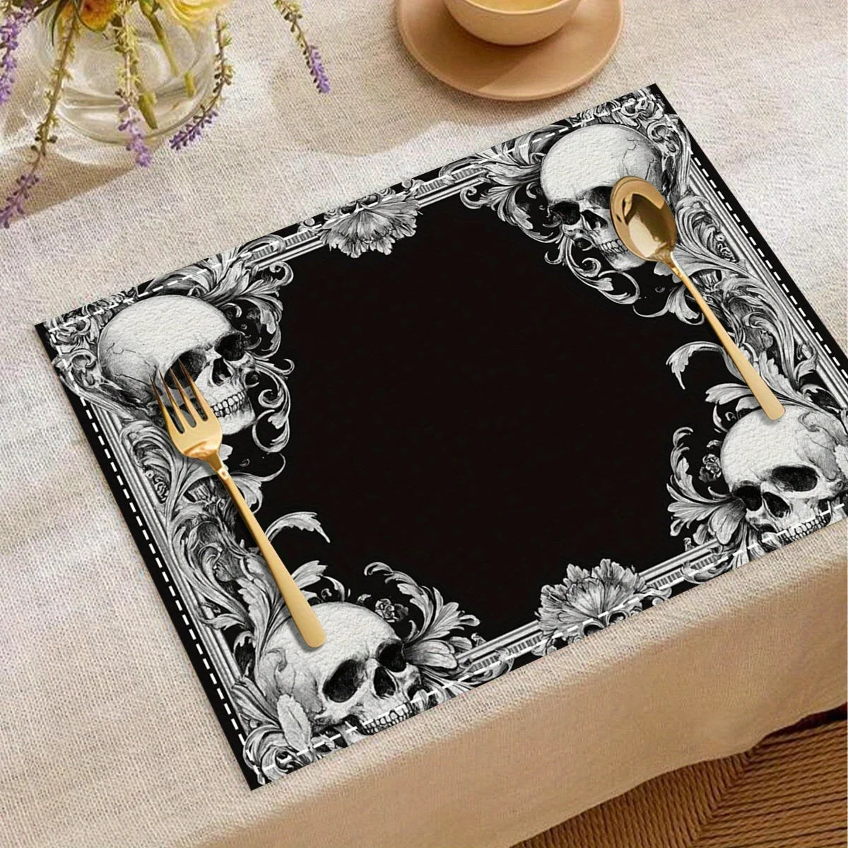A black placemat featuring a vintage skull and floral design with gold cutlery.