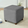 A square gray velvet ottoman slipcover resting on a light carpet.