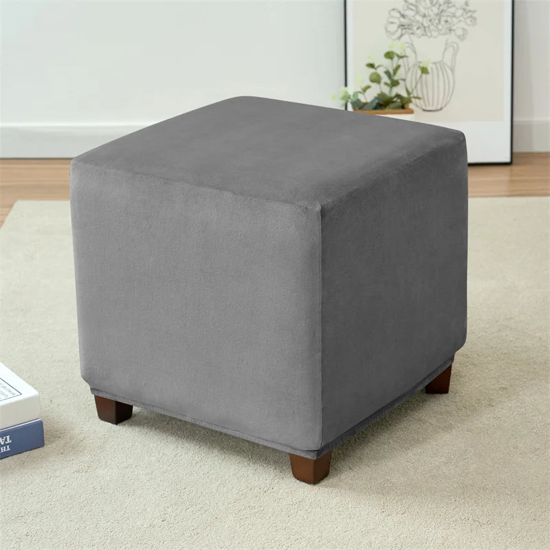 A square gray velvet ottoman slipcover resting on a light carpet.