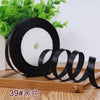 Rolls of black satin ribbon with white filling visible on a wooden surface