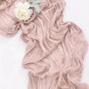 A flowing, dusty rose colored rustic gauze table runner with a white flower detail.