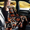 A woman sits in a car, holding and displaying a black and orange patchwork flannel throw blanket with Halloween designs.