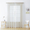Sheer white voile curtains hanging in a window with a wooden chair nearby.