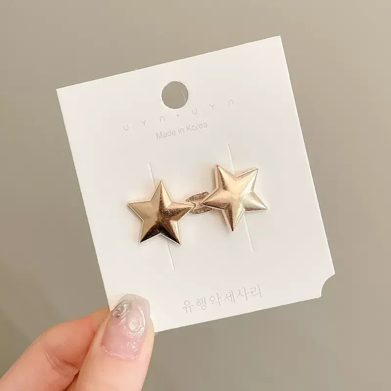 A pair of gold-toned star brooch pins displayed on a white card.