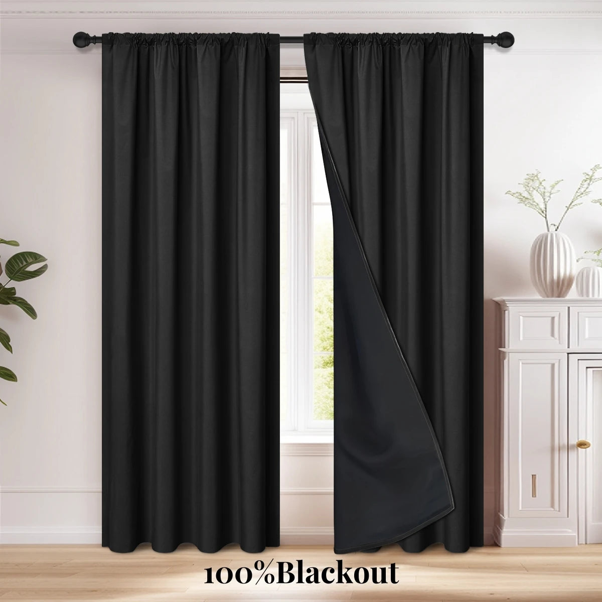 A pair of black blackout curtains hanging on a rod, shown next to a window.