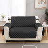 A modern sofa with a dark gray quilted slipcover and cream upholstery in a living room setting.