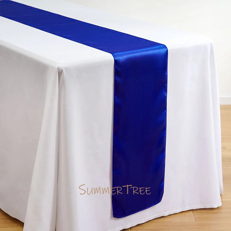 Elegant satin blue table runner draped across a white tablecloth.