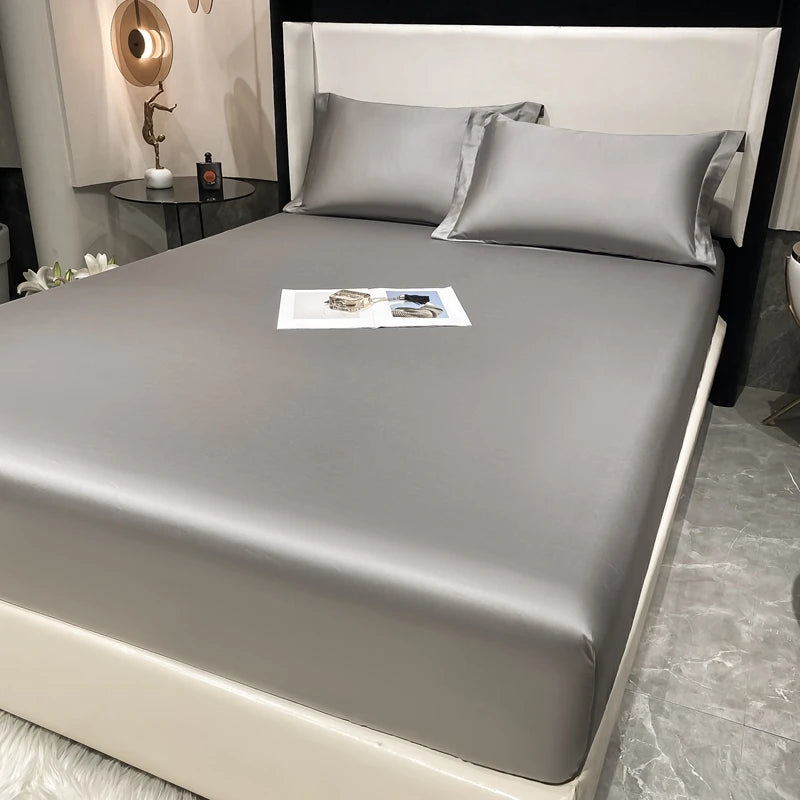 A luxury fitted sheet and pillow set in gray fabric displayed on a bed.