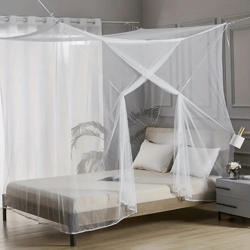 A sheer white mosquito net draped over a bed frame in a bedroom setting.