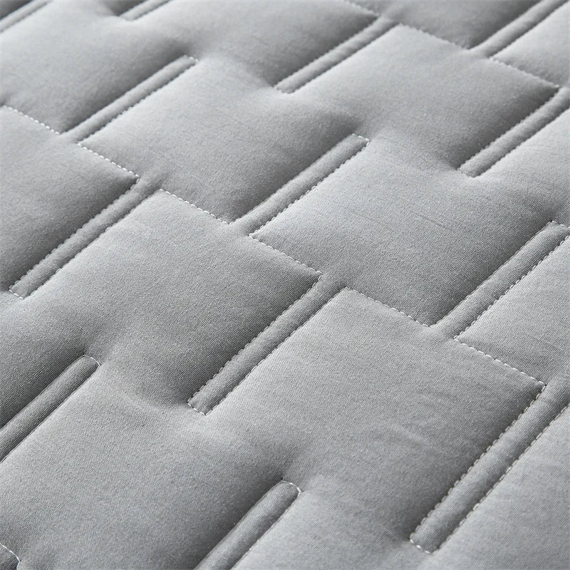 Close-up of light gray quilted fabric with a diamond pattern.