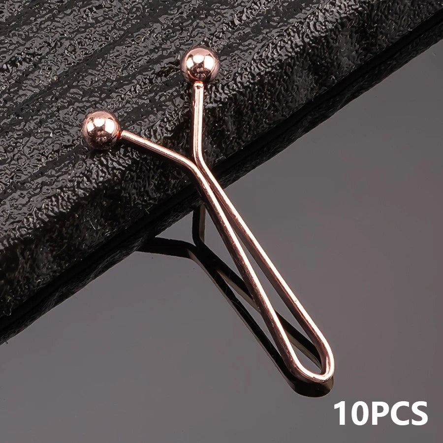 A set of ten rose gold metal lapel clips with spherical heads displayed on a dark surface.