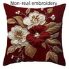 A deep red pillow featuring non-real embroidery of white and maroon floral designs on a dark background.