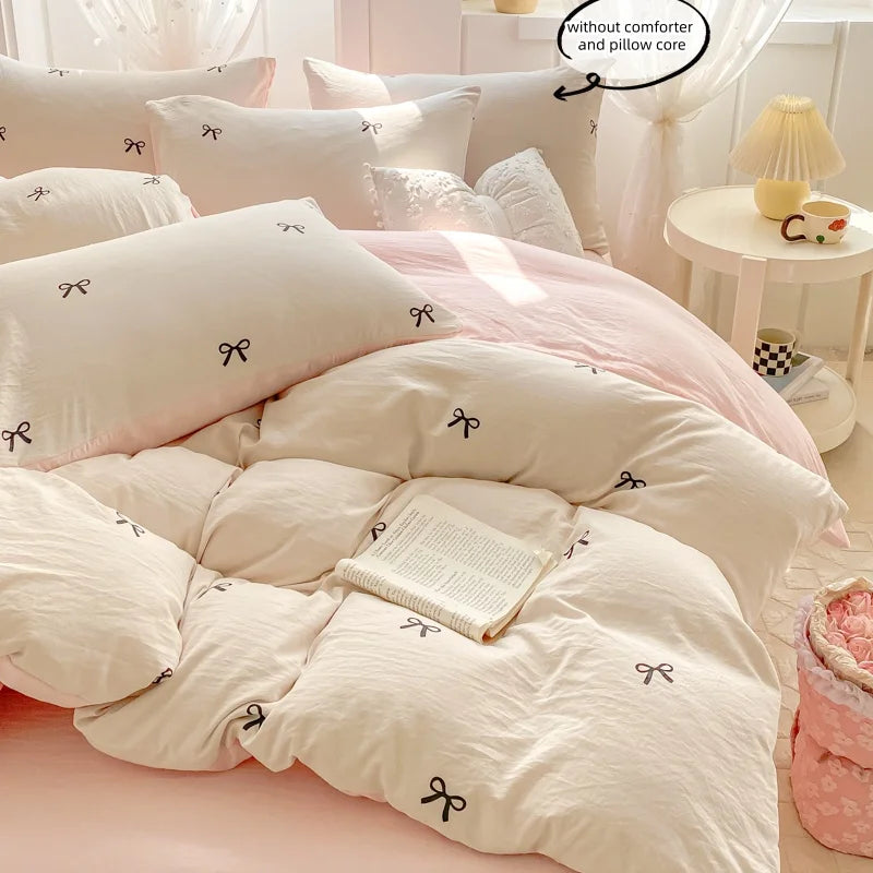 A set of three pink and white bedding pieces including a duvet cover, pillows, and a matching comforter with bowknot embroide