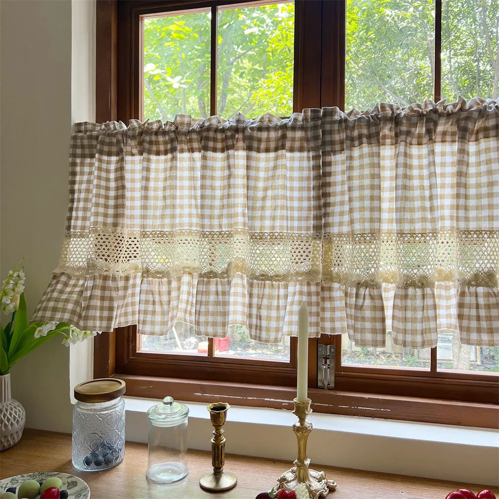 Beige gingham crochet lace curtain valance hanging over a window with greenery visible outside