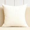 A cream-colored, vertically ribbed throw pillow cover resting on a light-colored sofa.