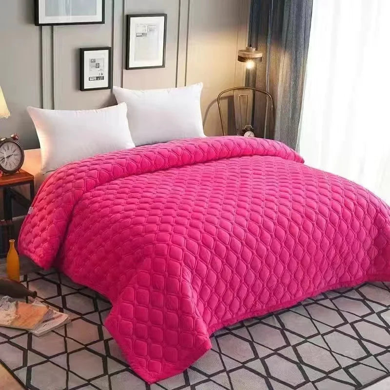 A bright pink plush velvet quilted bed cover blanket spread on a bed.