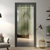 A vertical window with a sheer green lace curtain featuring sun and moon designs.