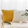 A yellow geometric plaid cushion cover resting on a white sofa with a white textured pillow and greenery.