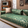 A luxury velvet sofa cover in deep green with gold damask patterns and decorative pillows.