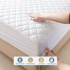A hand is pressing a white waterproof quilted mattress protector onto a bed surface.