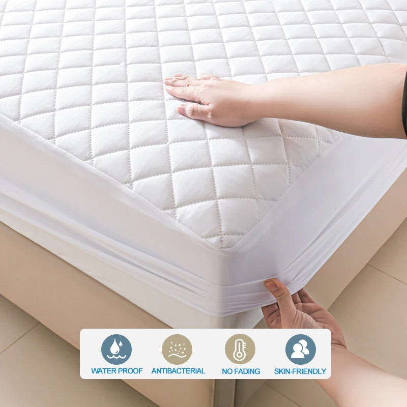 A hand is pressing a white waterproof quilted mattress protector onto a bed surface.