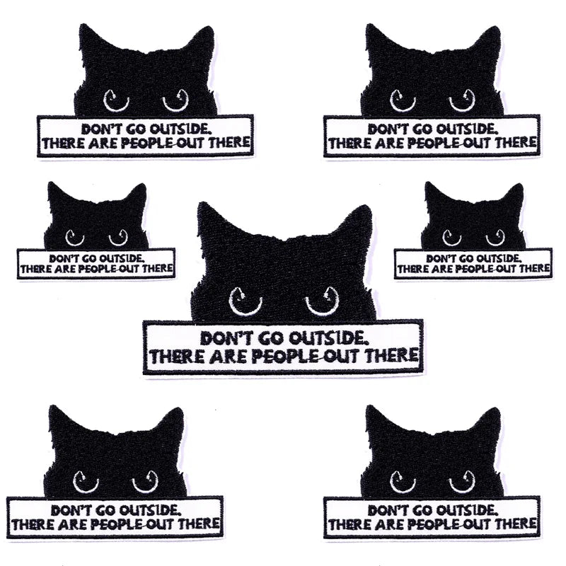 A collection of eight black cat face embroidery patches with text warning people not to go outside because there are people o