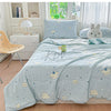 A light blue quilt blanket with a white pattern of clouds and stars is displayed on a bed in a bright room.